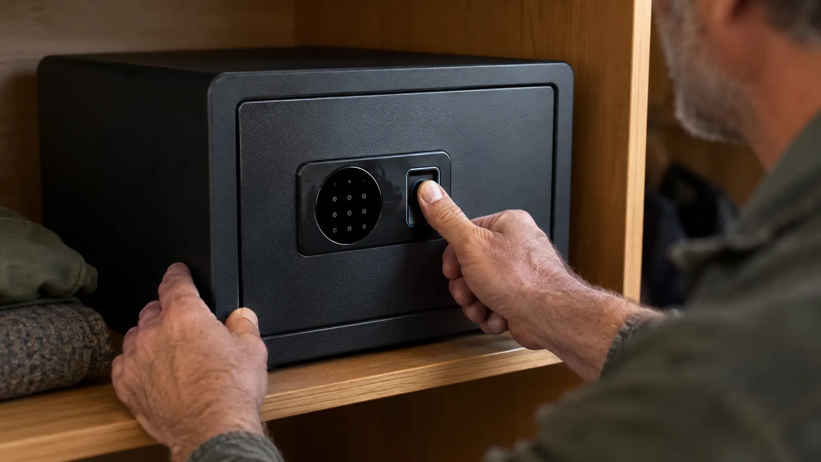 A close-up of a hand pressing a thumb to the fingerprint reader on the safe.