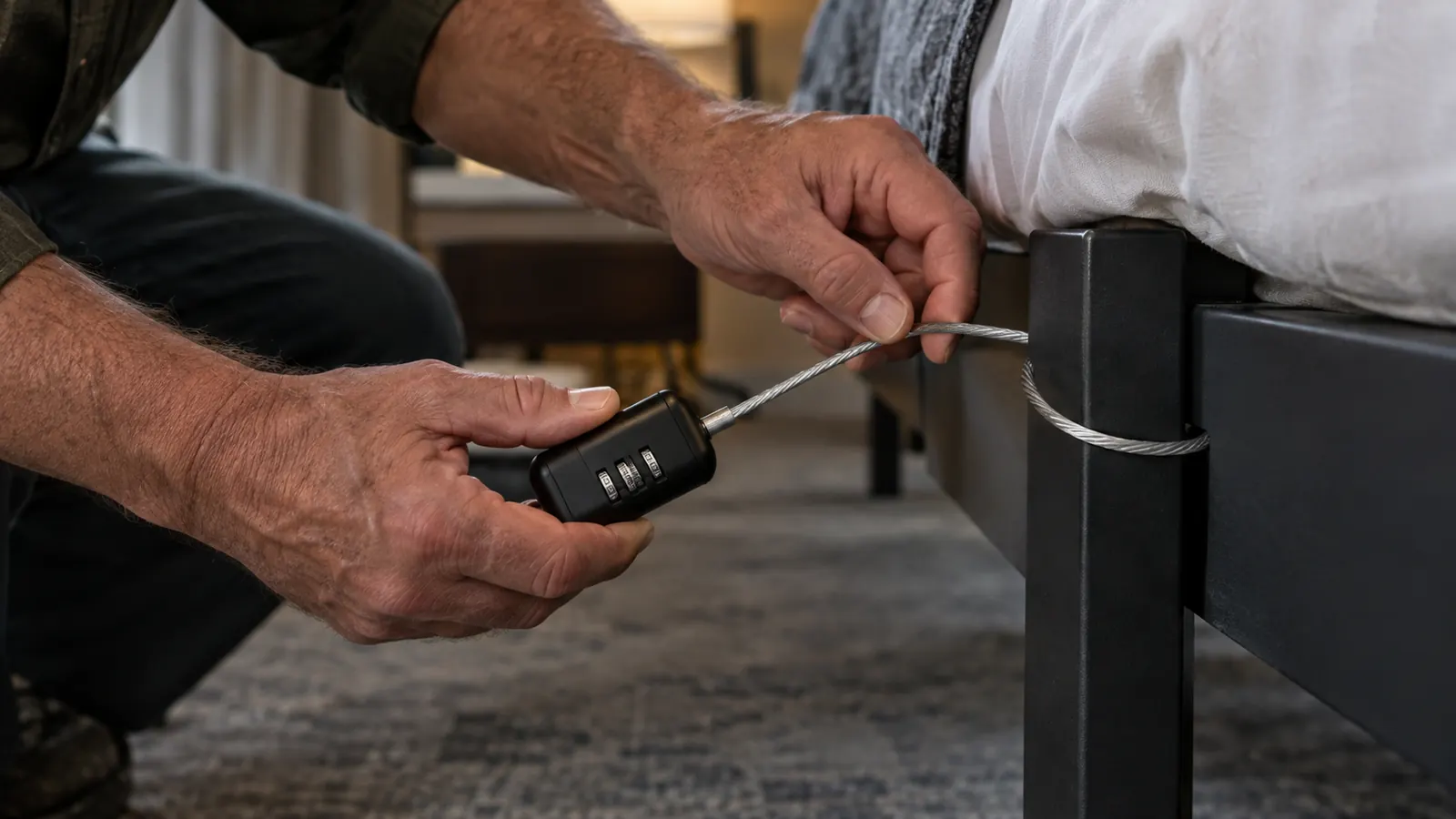 Hand threading the travel safe cable around a hotel bed frame