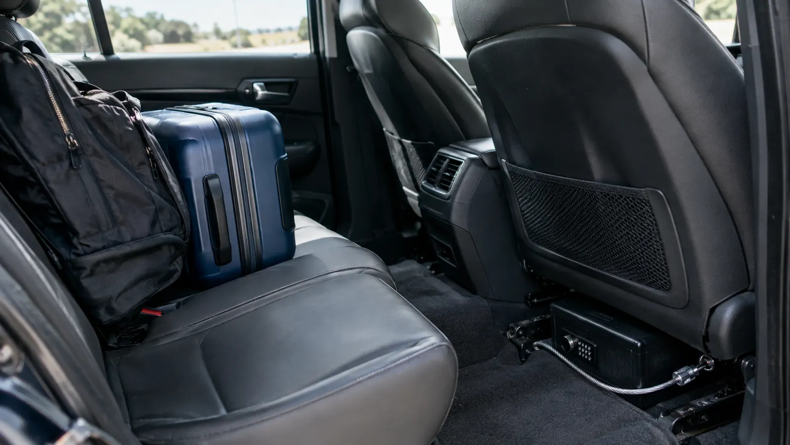 Travel safe cabled to a car seat frame with luggage in the back